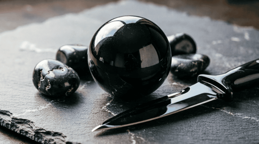 Esfera de obsidiana negra pulida junto a cuchillo de obsidiana mostrando su filo cortante