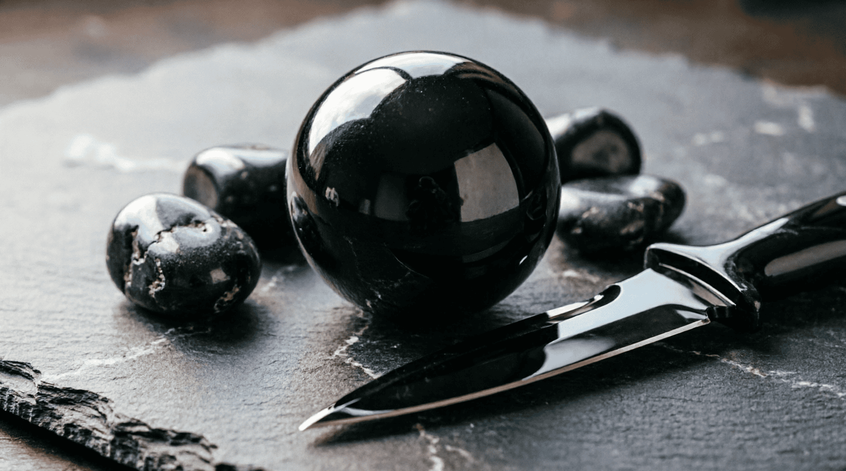 Esfera de obsidiana negra pulida junto a cuchillo de obsidiana mostrando su filo cortante