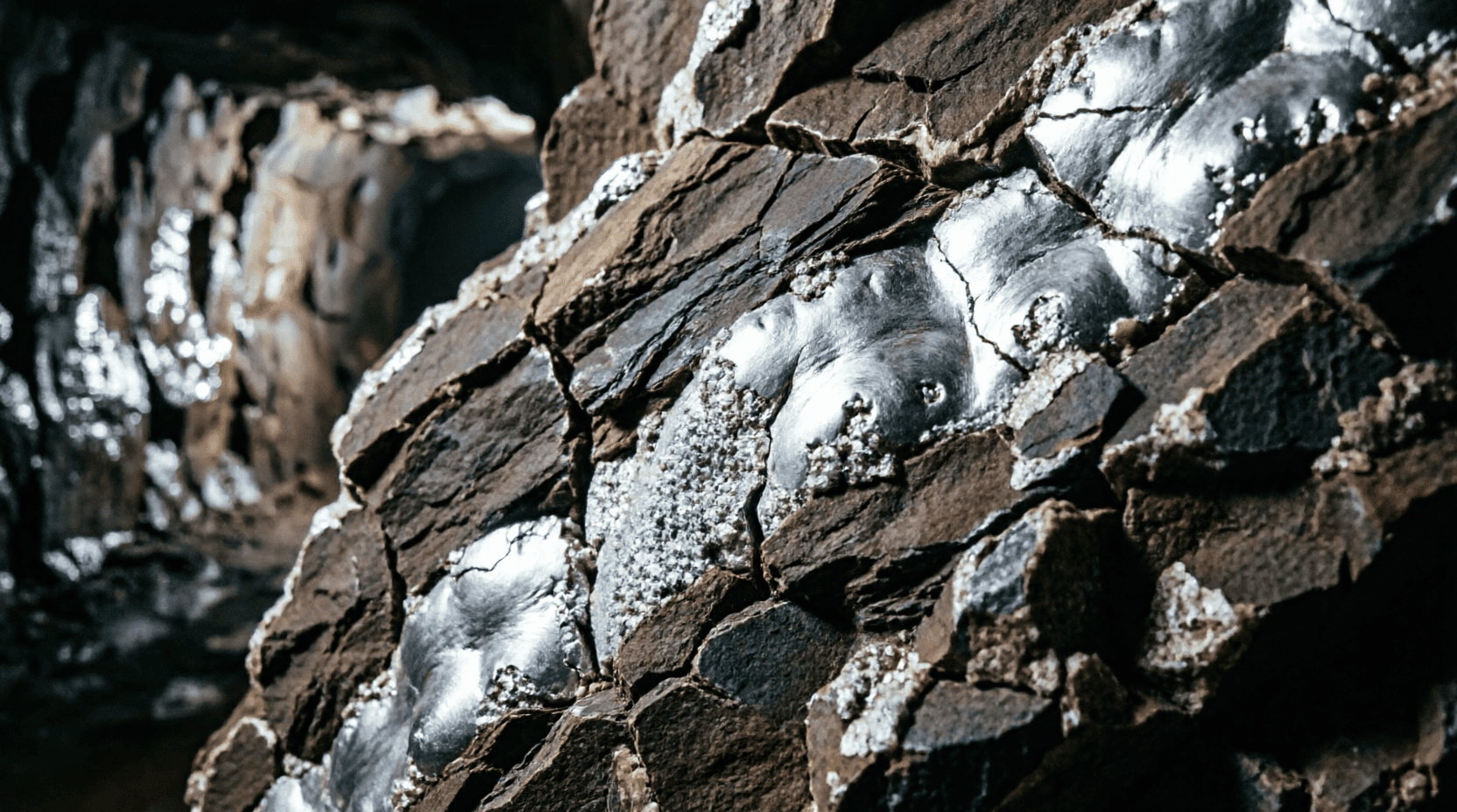 Mineral de plata en bruto en su veta natural subterránea Veta de mineral de plata en bruto en el interior de una mina oscura, origen de la plata en la naturaleza.